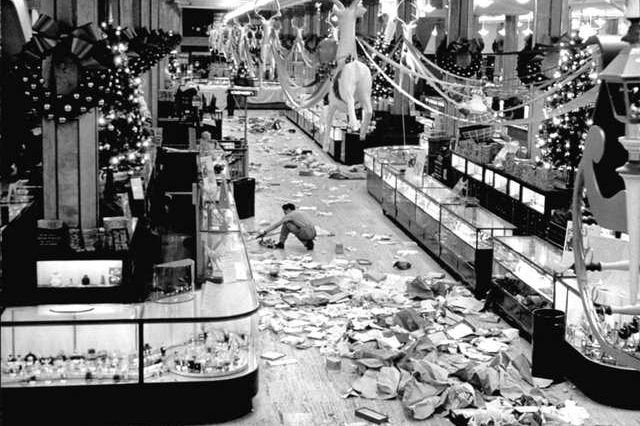"Macy's department store employee cleaning up piles of debris after the Christmas shopping rush."